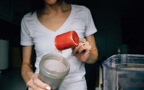 pouring protein powder into bottle 