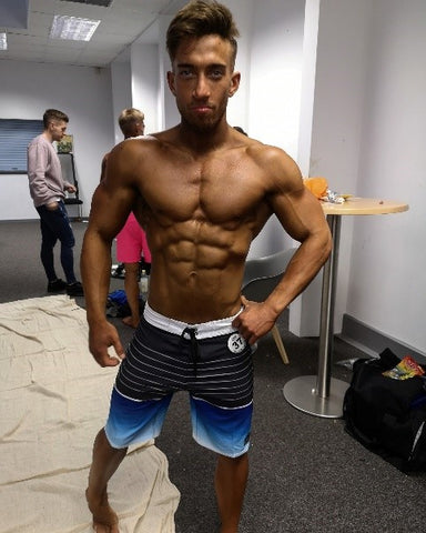 Ripped man posing in board shorts.