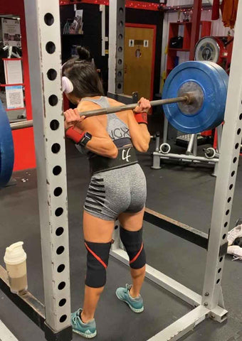 Female squatting with an NGX sports bra on and shorts